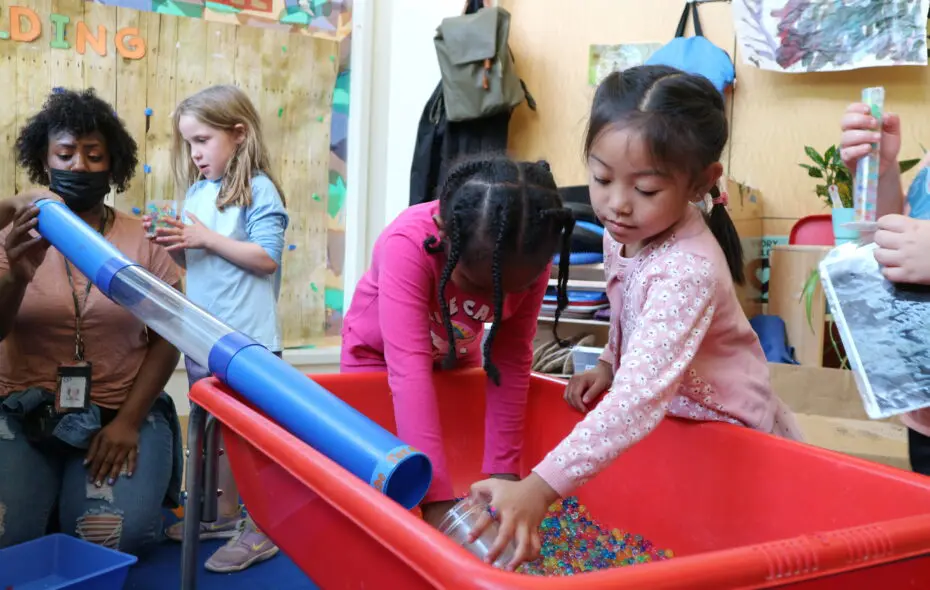 Two preschool girls play in a sensory table.
