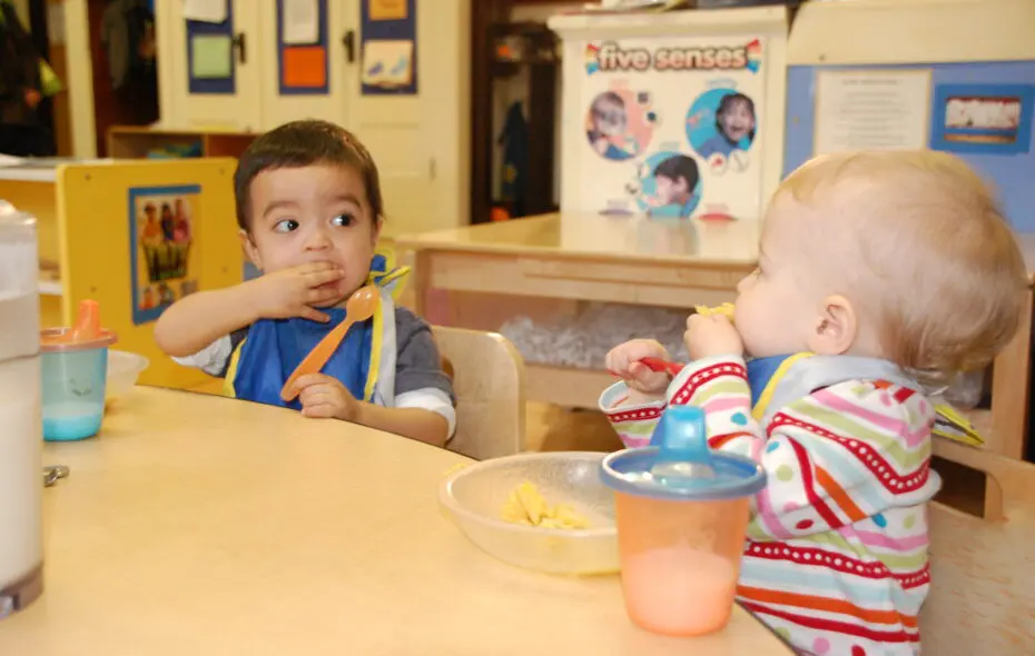 Toddlers seated at a table eating.