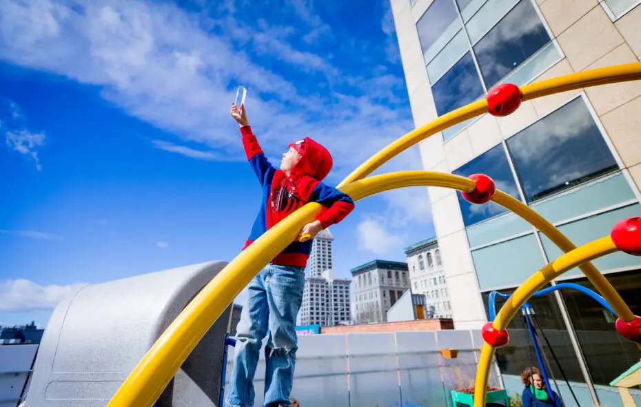 A boy playing on a playground with bright blue skies in the background.