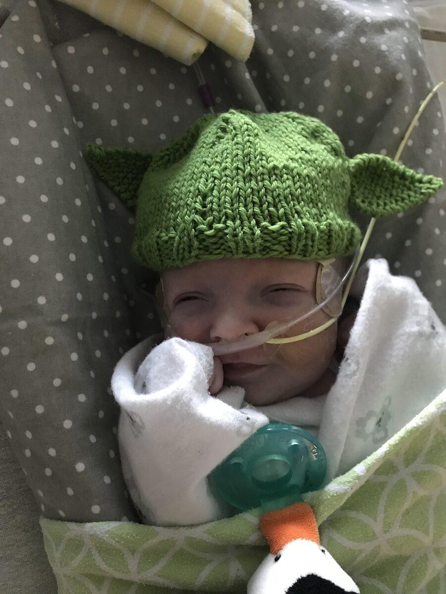 Newborn baby with oxygen and feeding tube wearing a hand-knit Yoda hat.