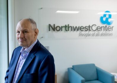 Patrick Dolan looking over his shoulder and standing in front of a Northwest Center sign.