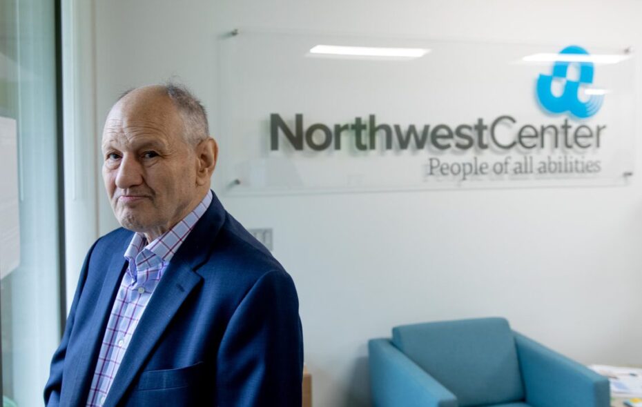 Patrick Dolan looking over his shoulder and standing in front of a Northwest Center sign.