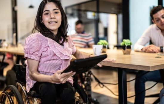 Woman on a wheelchair holding a tablet.