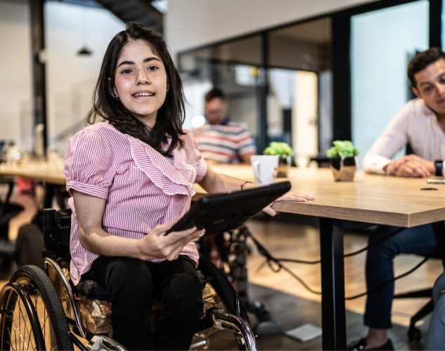 Woman on a wheelchair holding a tablet.