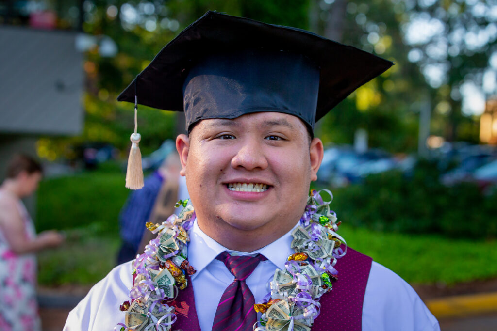 Man with graduation gown smiling.