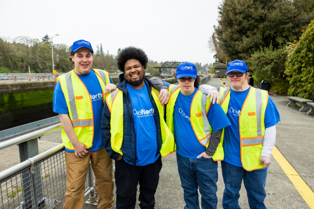 Four men wearing construction work gear smiling.